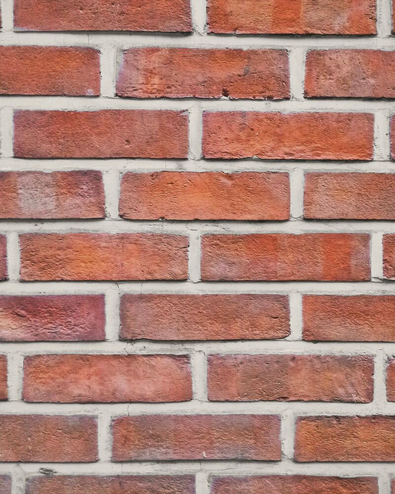 Mur en briques rouges aux joints clairs, nets et réguliers.