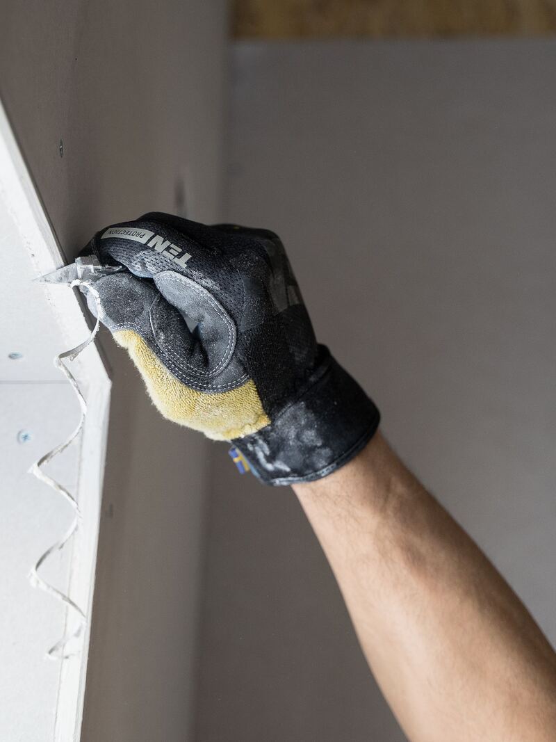 Pose de plaques de plâtre, main gantée en gros plan.